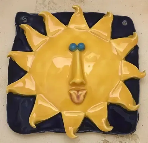 Glazed clay sun face with blue eyes by Mary Douglas